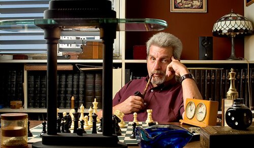 Photograph of Yakir Aharonov seated at a chessboard in a study